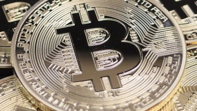 Physical silver bitcoin coin on a circuit board — IOST v4.0.0 mandatory hard fork and a 106% day