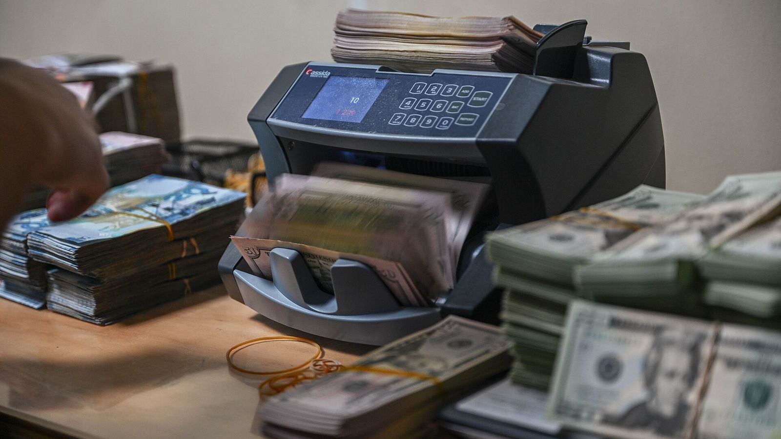 Banknotes moving through a currency-counting machine — US and UK banks put tokenized deposits on bank-built settlement rails in September 2026