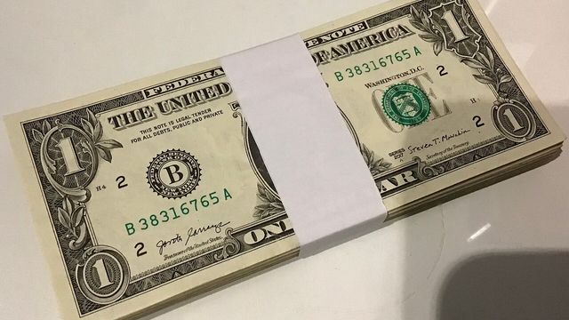 A stack of 80 US one-dollar bills in a paper banknote strap — Cardano's RealFi USDr dollar is scheduled to launch on mainnet on October 1, 2026