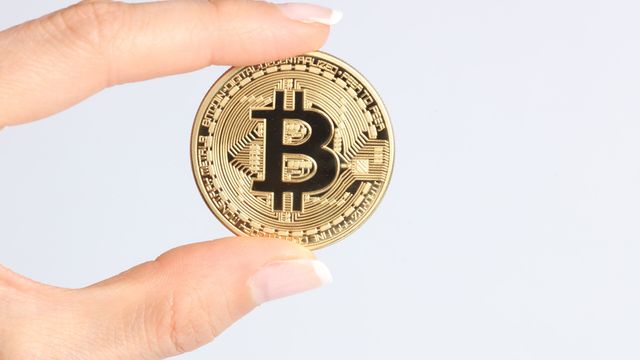 Gold physical bitcoin coin held between two fingers — Starknet STRK, Bitcoin staking and the October 15 unlock