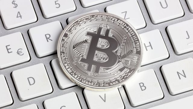 A silver physical bitcoin coin resting on a white laptop keyboard — the XRP Ledger's security patch slipped past its 23 October activation date