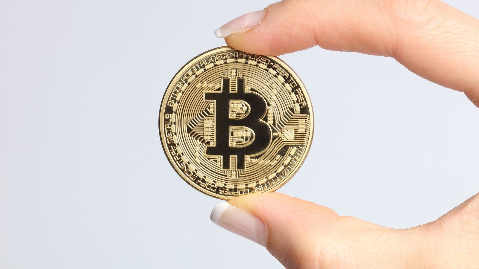 A gold physical crypto coin held between two fingers — free SUI faucet claims every 15 minutes on EarnCrypto.dev