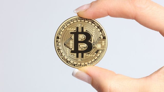 A gold physical crypto coin held between two fingers — free SUI faucet claims every 15 minutes on EarnCrypto.dev