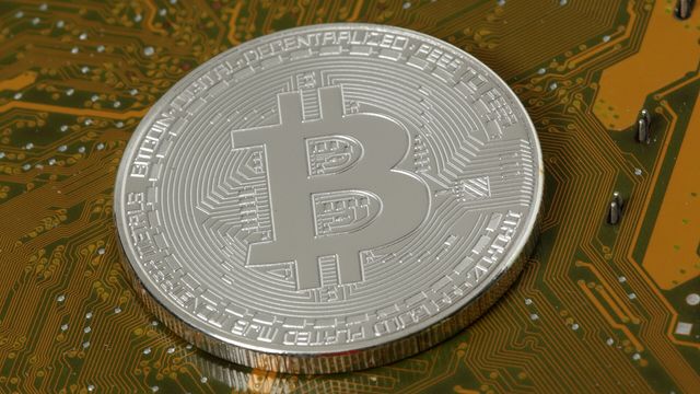 Silver physical crypto coin resting on a gold circuit board — Solana's Alpenglow consensus upgrade activating on 21 October 2026