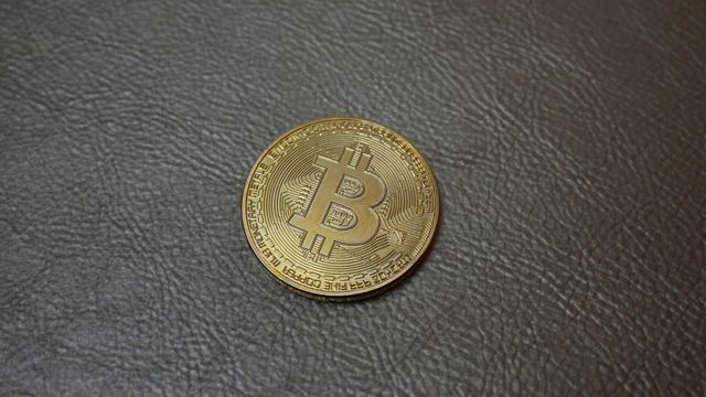 Physical gold bitcoin coin resting on grey leather — Celestia TIA data availability token after Derive V3 adoption
