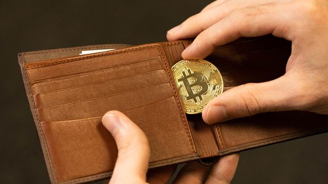 A gold physical bitcoin coin being placed into a leather wallet — U.S. spot bitcoin ETF inflows and exchange supply in September 2026