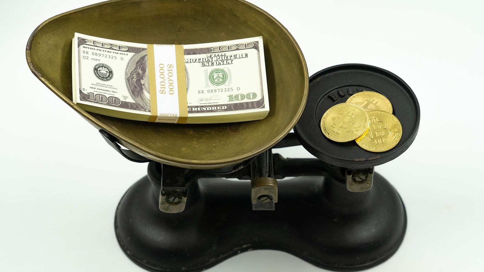 Bitcoin medallions weighed against a stack of US dollar bills — the Fed rate hike, the CLARITY Act defeat and the $76,700 line that decides Bitcoin's next move