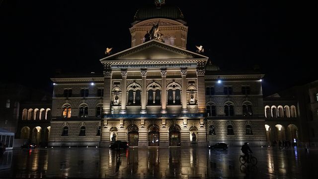 The Swiss Federal Palace in Bern at night across the wet Bundesplatz — FINMA's approval of Switzerland's first retail Bitcoin ETF