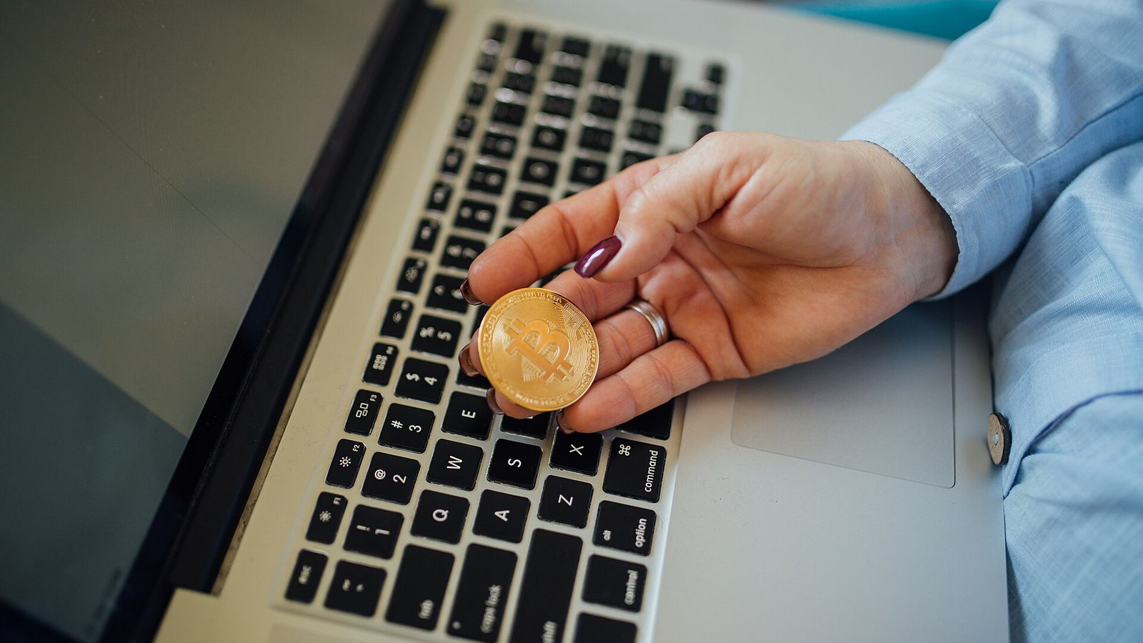 Physical Bitcoin coin in a hand above a laptop — Binance opened HYPE spot trading in USDT, USDC and TRY with a Seed Tag on September 24, 2026