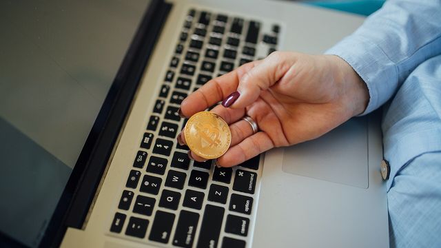 Physical Bitcoin coin in a hand above a laptop — Binance opened HYPE spot trading in USDT, USDC and TRY with a Seed Tag on September 24, 2026