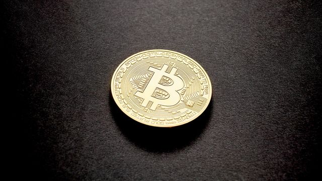 A physical gold Bitcoin coin on a dark surface — Bitcoin's fourth straight green September and the $87,395 level October has to clear