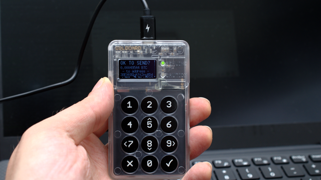 A hardware wallet held in front of a laptop — Aptos unlocks 11.31 million APT on 11 October 2026, the last insider cliff in its vesting schedule
