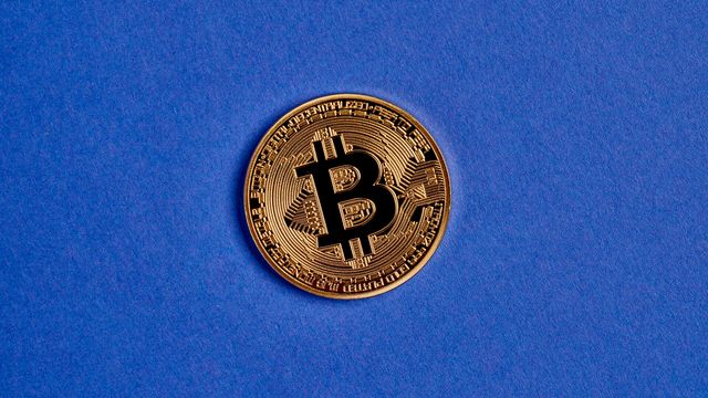 A physical gold bitcoin coin on blue fabric — Zcash NU7 mainnet activation decision for 25-second blocks