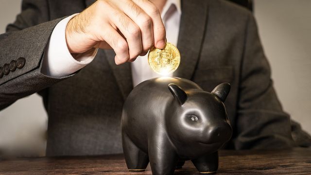 A person dropping a physical Bitcoin medallion into a piggy bank — record spot Bitcoin ETF inflows in September 2026