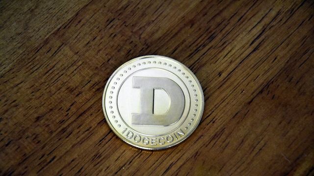 Physical Dogecoin coin on a wooden desk — eleven live airdrop campaigns tracked on EarnCrypto