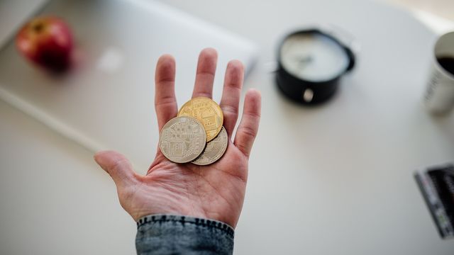 A hand holding several different physical cryptocurrency coins — breadth across the top 100 coins as 87 of them turned green in September 2026