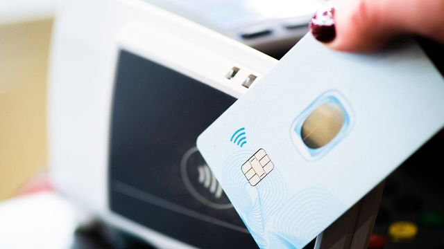 A hand tapping a contactless bank card on a payment terminal — Plasma's multi-currency stablecoin card deal with Stripe