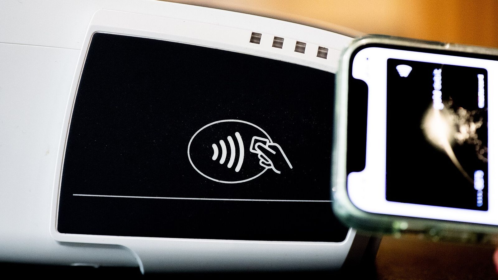 Contactless payment terminal with a phone tapping to pay — the OCC's final GENIUS Act stablecoin rule and its two-business-day redemption standard