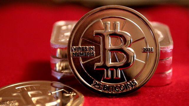 Physical 25 BTC Casascius gold rounds on red velvet — seven of 77 top-100 tokens green while bitcoin lost 1.38%