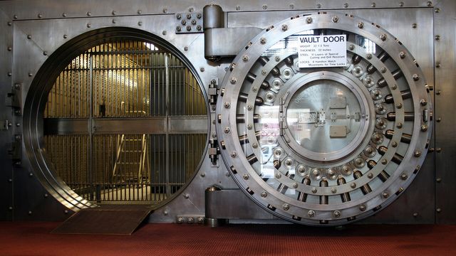 Steel bank vault door with polished circular bolts — crypto lending vaults holding $10 billion in deposits