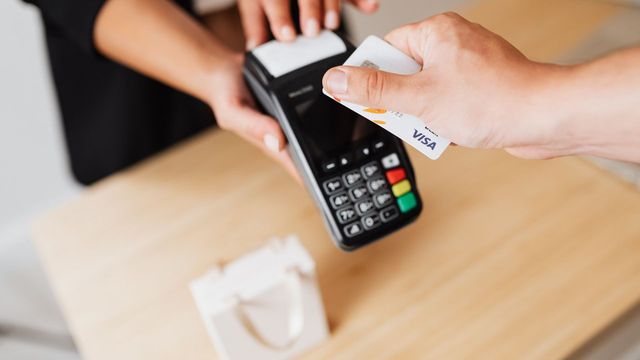 Hands using a contactless payment terminal with a card — U.S. Bank settling a cross-border payment with its own stablecoin on Stellar