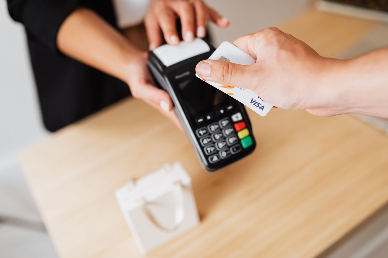 Hands using a contactless payment terminal with a card — U.S. Bank settling a cross-border payment with its own stablecoin on Stellar