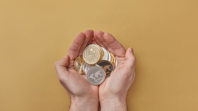 Hands holding a spread of crypto coins — AVAX triple-touching the $7.00 shelf