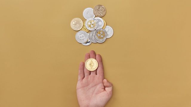 A hand holding a crypto token above scattered coins — Pi Network activating Protocol 27 on September 15