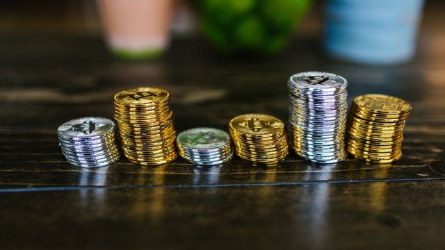 A pile of crypto coins on a wooden table — LINK double-topped at $12.62 above the $11.00 neckline