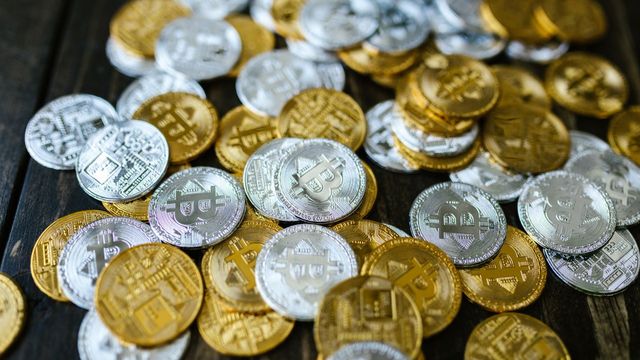 Scattered gold and silver crypto coins on a wooden table — DOGE coiling under the $0.090 gate