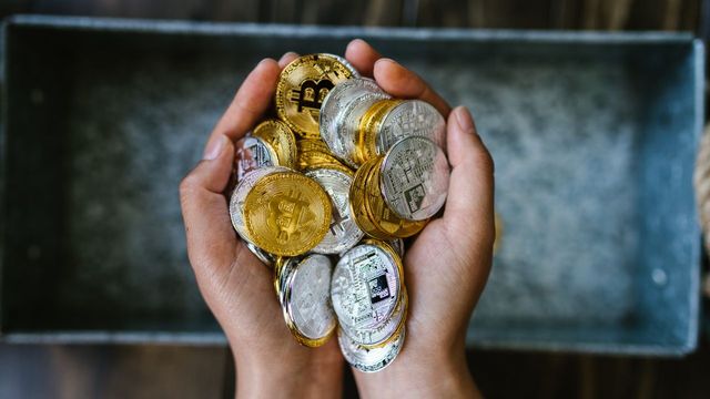 Hands holding gold and silver crypto coins — Jito's BAM preconfirmations covering 34% of Solana's staked SOL